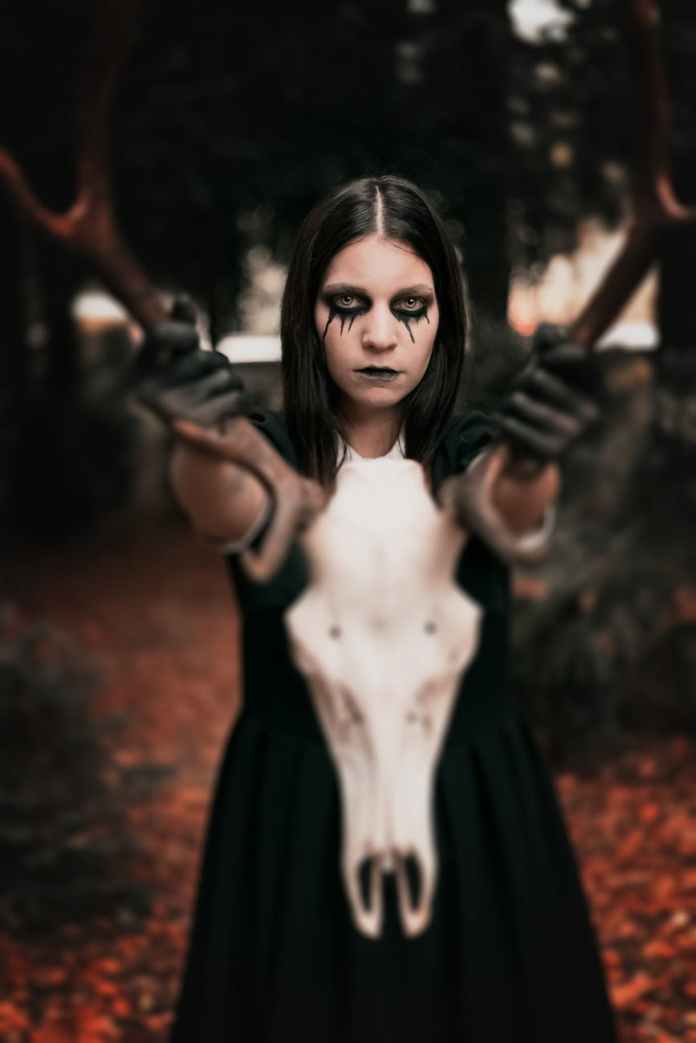 woman in black dress holding animal skull